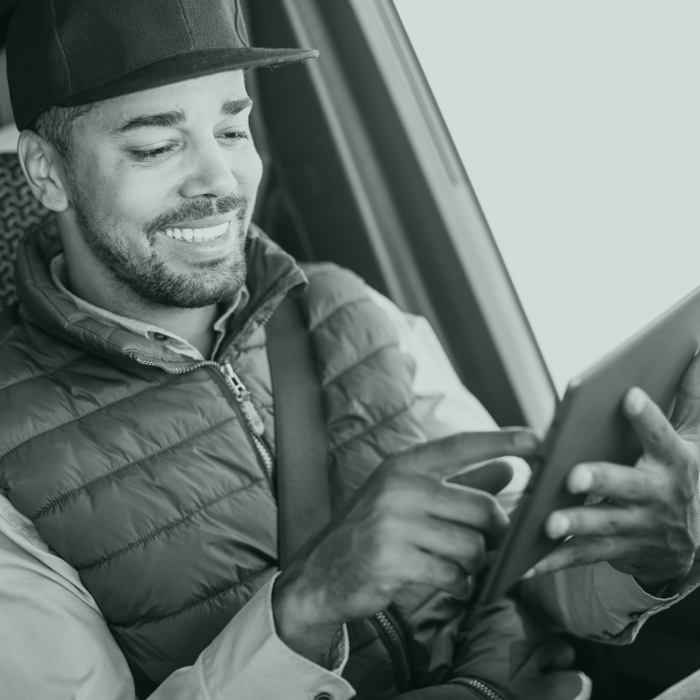 Homme souriant dans une voiture avec une tablette dans les mains