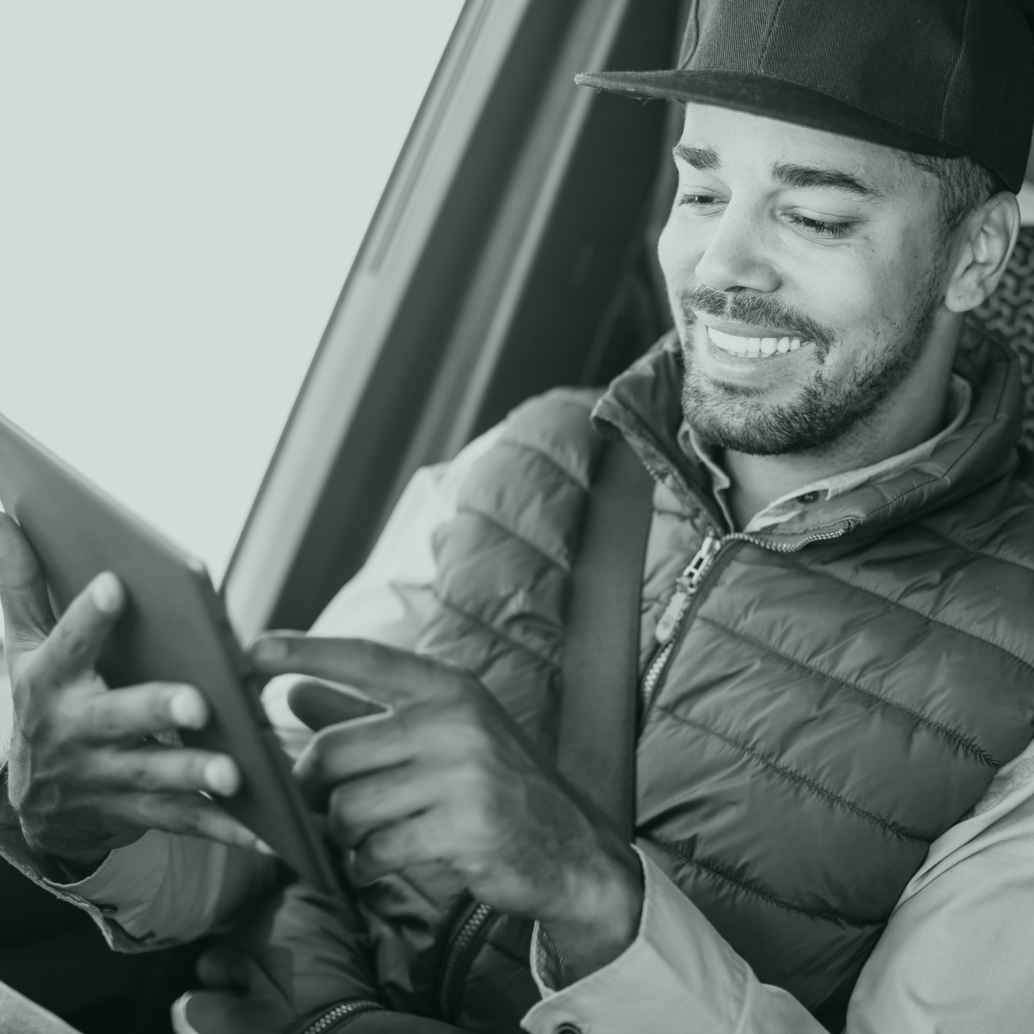 Homme souriant dans une voiture avec une tablette dans les mains