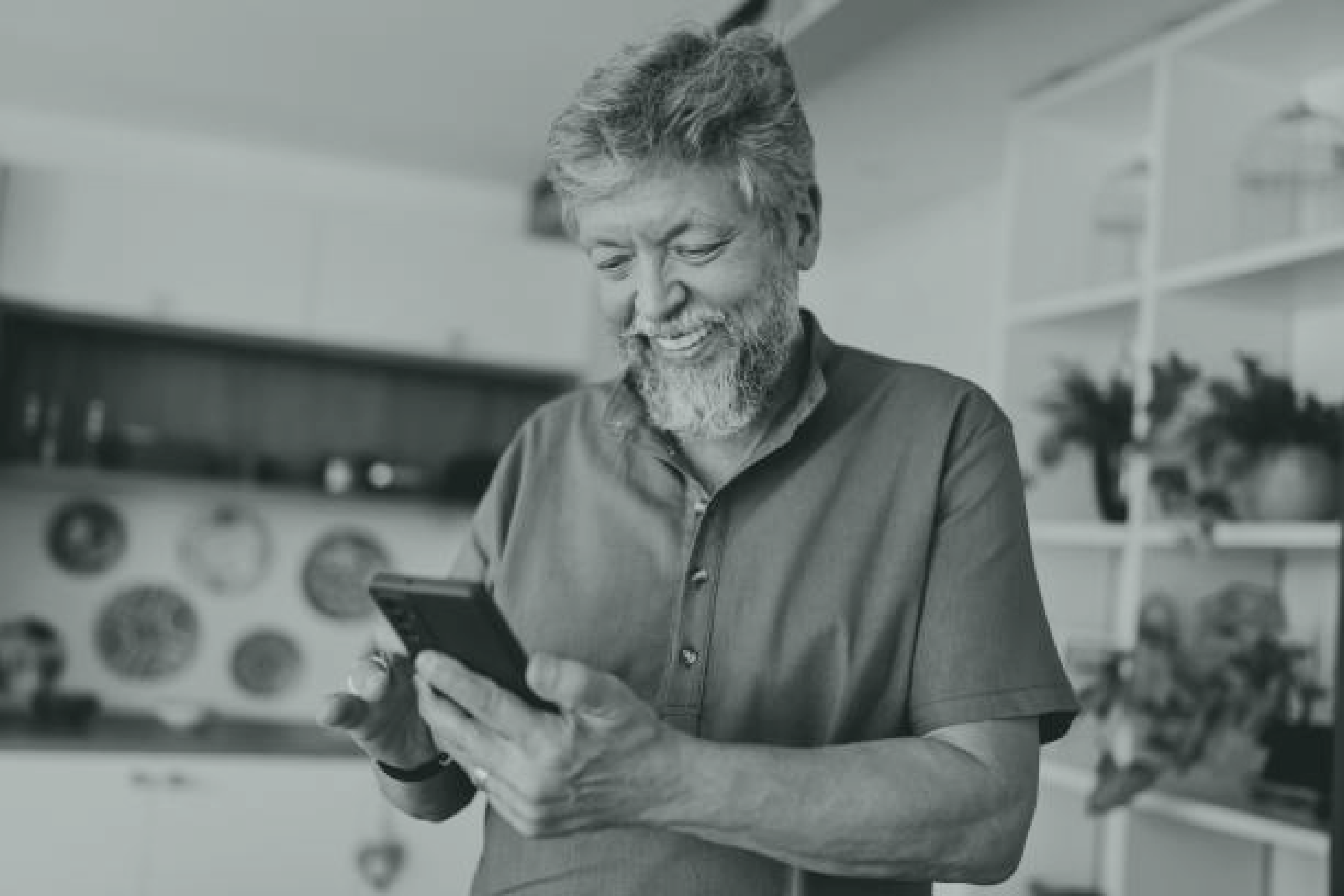 Homme souriant regardant son téléphone dans sa cuisine