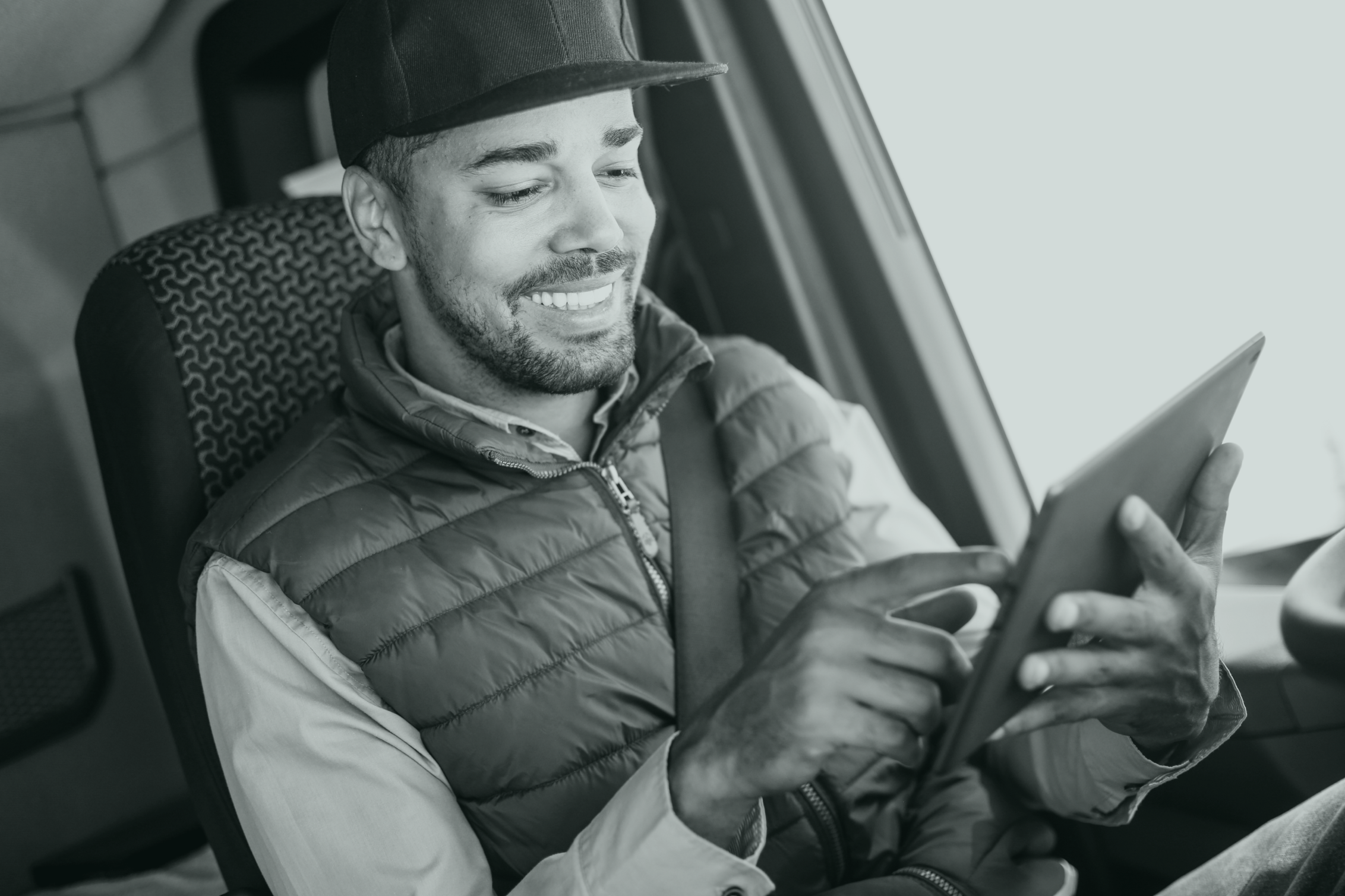 Smiling man in a car with a tablet in his hands