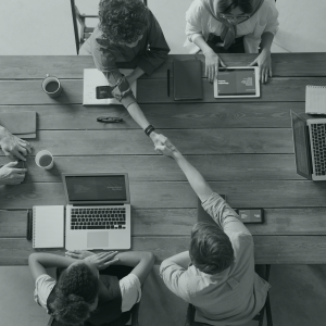 Vue plongeante d'une table autour de laquelle se trouvent plusieurs personnes, dont deux qui se serrent la main