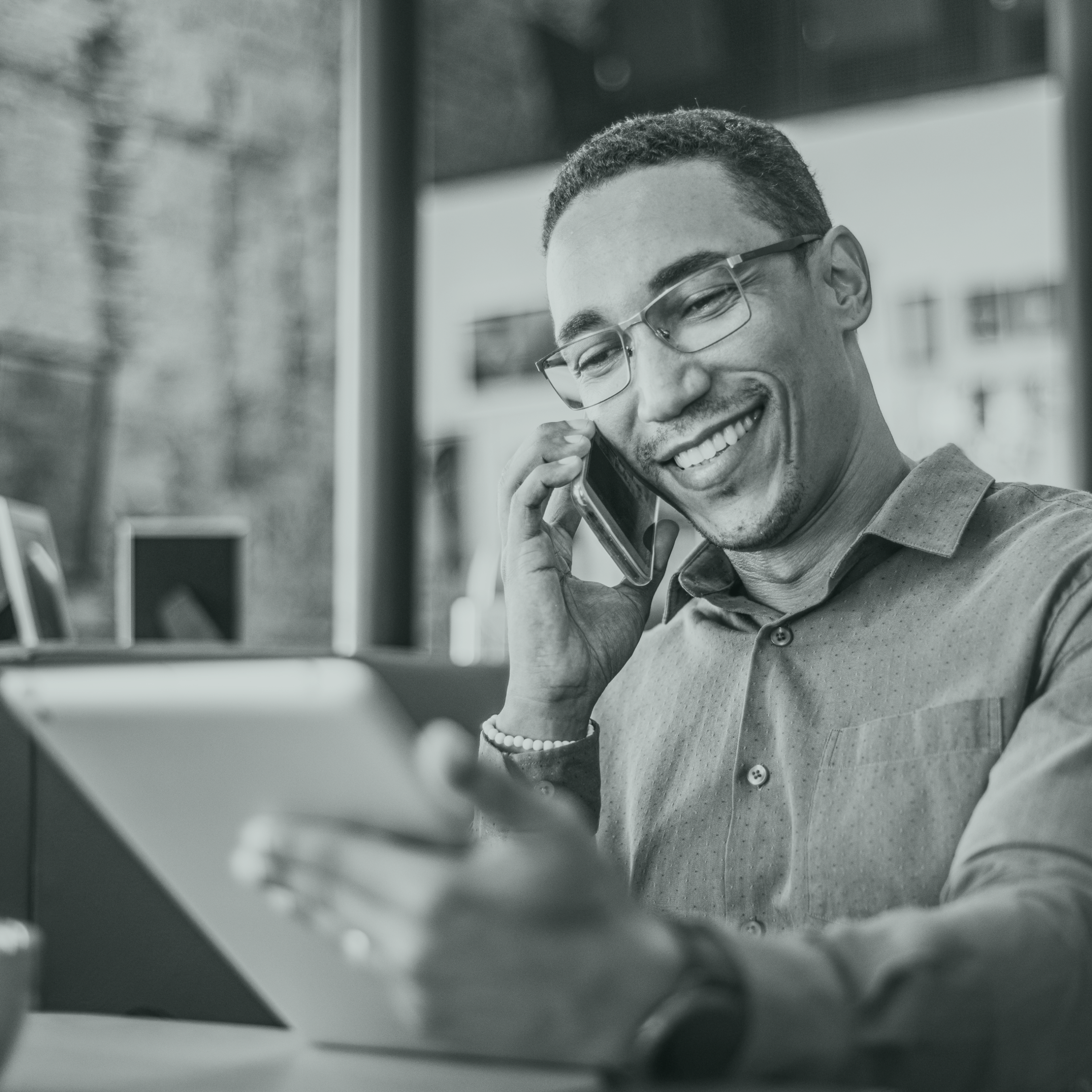 Smiling man on the phone, holding a tablet in one hand