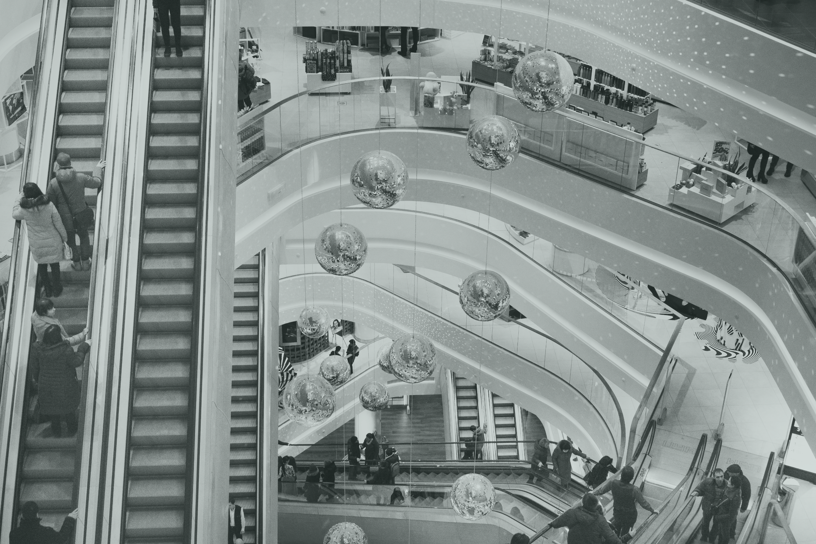 A bird's-eye view of a multi-storey shopping mall with escalators and hanging decorations