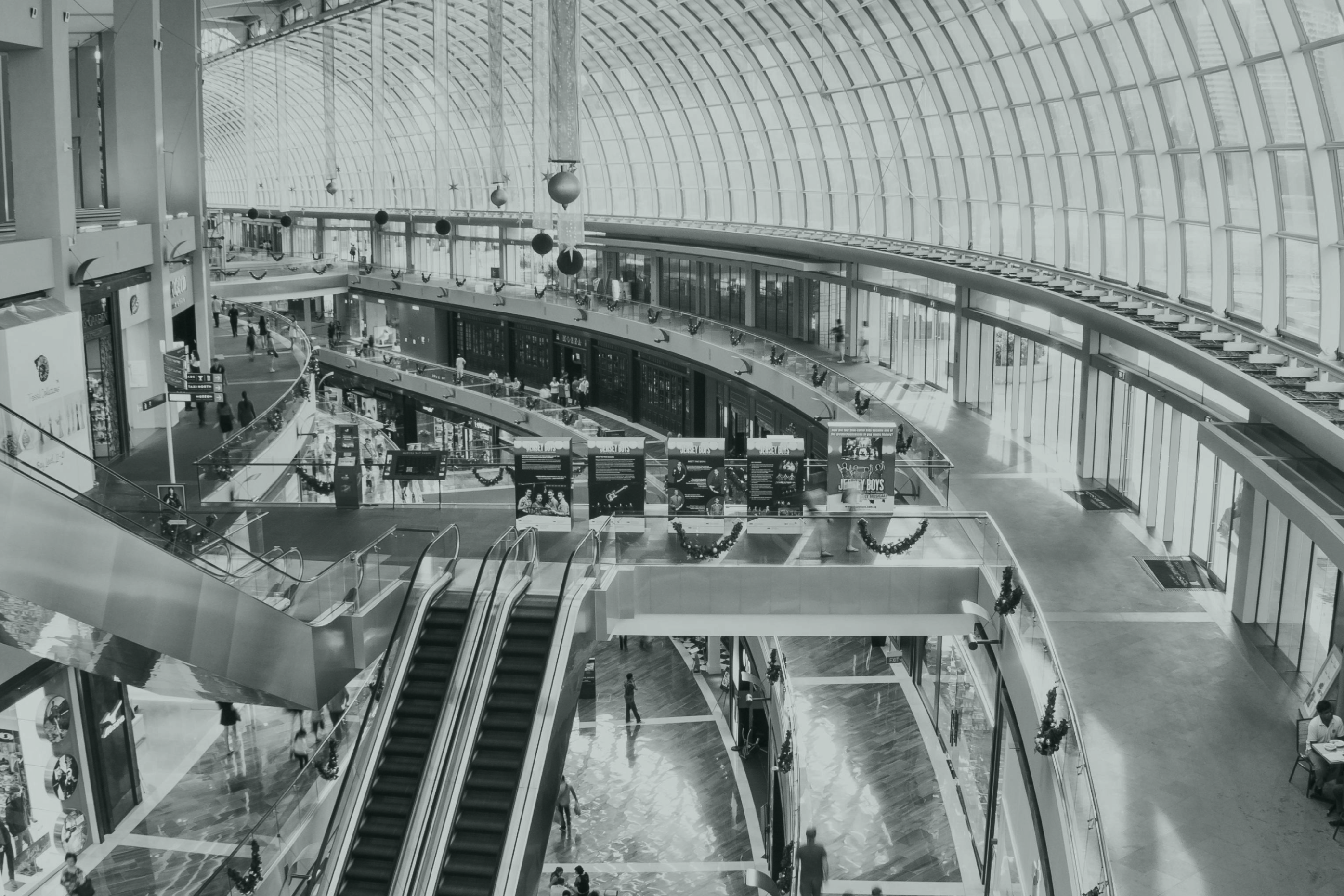 A bird's-eye view of a shopping mall with escalators, where people are moving around